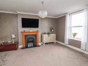 a living room with a fireplace and a flat screen tv at Ty Canol in Rhyl