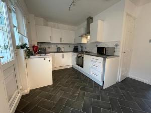 a kitchen with white cabinets and a tile floor at Ferguson House in Airdrie