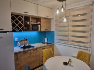 a kitchen with a white table and yellow chairs at Vila Jahor Apartman Miro in Jahorina