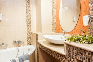 ein Badezimmer mit Waschbecken, Spiegel und Badewanne in der Unterkunft Zante Plaza Hotel & Apartments in Laganas