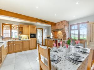 a kitchen with a dining room table with chairs and a kitchen with a brick wall at The Farm House in Shipton under Wychwood