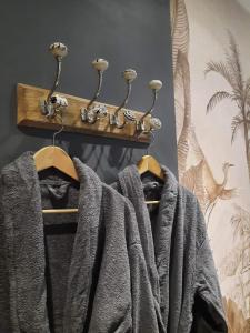 Un perchero con toallas grises colgadas en una pared en lovebirds spa, en Vincey