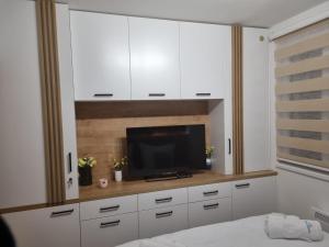 a bedroom with a tv and white cabinets at Vila Jahor Apartman Miro in Jahorina