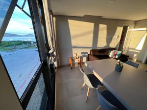 Zimmer mit einem Tisch und Stühlen sowie einem großen Fenster in der Unterkunft Apartamento Frente Mar Vista Lateral in Bombinhas