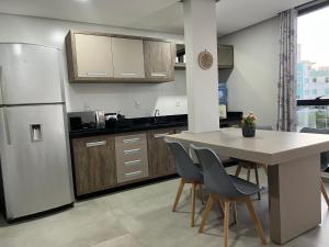 eine Küche mit einem Tisch und Stühlen sowie einem Kühlschrank in der Unterkunft Apartamento Frente Mar Vista Lateral in Bombinhas
