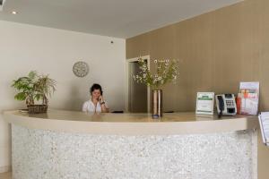 Eine Frau, die auf einem Handy hinter einer Theke spricht in der Unterkunft Zante Plaza Hotel & Apartments in Laganas + 32 Fotos