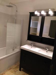 ein Badezimmer mit einem Waschbecken, einem Spiegel und einer Badewanne in der Unterkunft Piolenc Très bel appartement in Piolenc