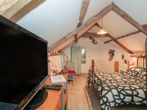 a bedroom with a bed and a flat screen tv at The Coach House in Somerton