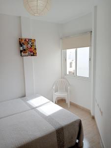 プエルト・デル・ロサリオにあるCasa Albertoのベッドルーム1室(ベッド1台、椅子、窓付)