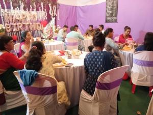 grupa ludzi siedzących przy stolikach w pokoju w obiekcie Mhatre Cottage Alibag Mani w mieście Alibag