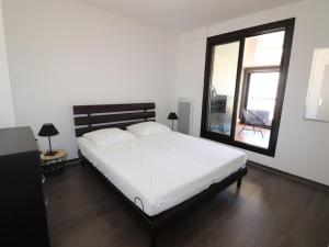 1 dormitorio con cama blanca y ventana grande en Appartement Le Grau-du-Roi, 3 pièces, 6 personnes - FR-1-307-135, en Le Grau-du-Roi