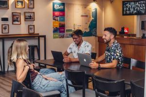 a group of people sitting at a table with laptops at Hostel Playa Grande Güemes in Mar del Plata