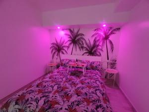 Dieses lila Zimmer verfügt über ein Bett mit einem Tisch und Palmen. in der Unterkunft Sweet Apt Charco by flamingo house in Arrecife
