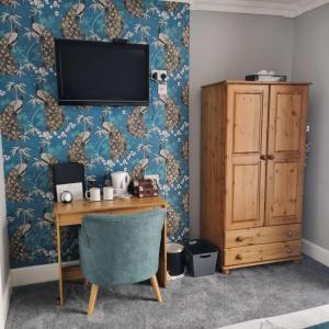 een kamer met een bureau en een tv aan de muur bij St Vincent Guest House in Lynton