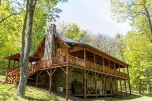 a log cabin in the woods with a wrap around deck at A Beary Good Time in Boone