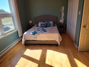 a bedroom with a bed with blue pillows and a window at Motel de la mer in Rimouski