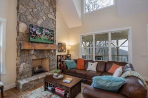 a living room with a couch and a stone fireplace at Alpine Gorge View in Blowing Rock