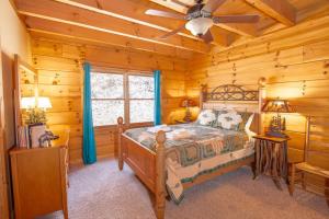 Cette cabane en rondins comprend un lit et un ventilateur de plafond. dans l'établissement Beech View Retreat, à Zionville