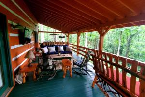 a porch of a cabin with a couch and chairs at Big Timber Creek Cabin in Sugar Grove