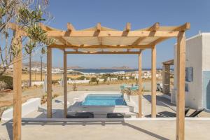 een houten pergola boven een zwembad met een zonneklep bij SAIL VILLA in Naousa