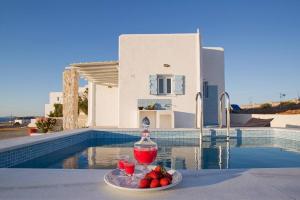 une assiette de fruits sur une table à côté d'une piscine dans l'établissement SAIL VILLA, à Náoussa