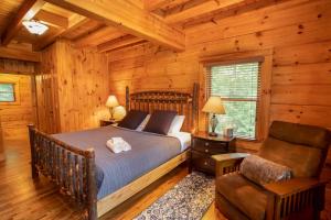 1 dormitorio en una cabaña de madera con 1 cama y 1 silla en Blessed Way Escape, en West Jefferson