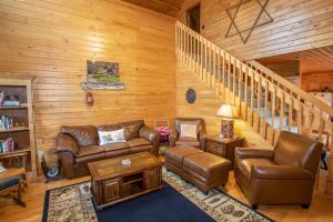 a living room with leather furniture and a staircase at Boots Off Bungalow in Boone