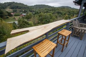 a wooden bench on a deck with a table and a stool at Boots Off Bungalow in Boone