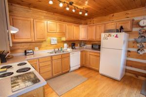 a kitchen with wooden cabinets and a white refrigerator at Boots Off Bungalow in Boone