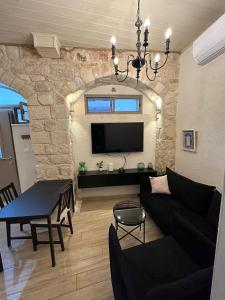 a living room with a black couch and a tv at בר יוחאי in Safed