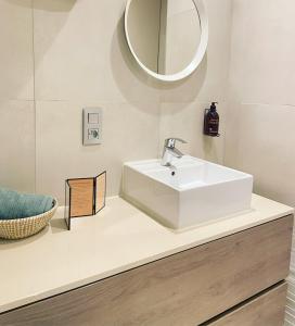 een badkamer met een witte wastafel en een spiegel bij Studio Delfien in Oostduinkerke