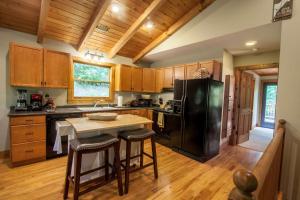 a kitchen with a black refrigerator and wooden cabinets at Creek Sound Chalet in Blowing Rock