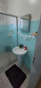 een badkamer met een witte wastafel en een douche bij Casa aconchegante e pratica in Cascavel