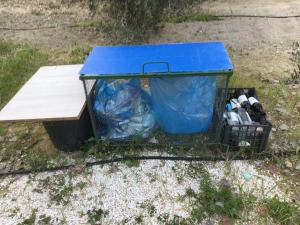 una mesa azul con botellas y un cubo de basura en Pervolaris Cottages 1, en Goudhi