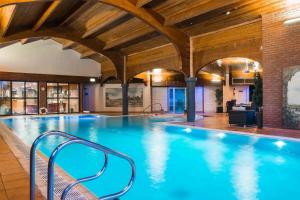 a large swimming pool in a building with wooden ceilings at Abbey Hotel Golf & Spa in Redditch