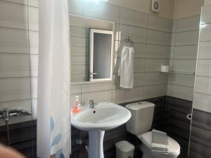 a bathroom with a sink and a toilet and a mirror at Lovely Anna's Apartments in Sarandë