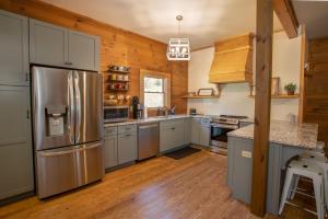 eine Küche mit einem Edelstahlkühlschrank und Holzwänden in der Unterkunft Happy Apple in Blowing Rock