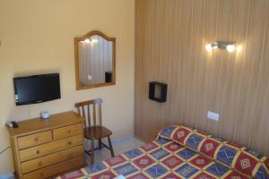 a bedroom with a bed and a dresser and a mirror at Hostal Cristina in Denia
