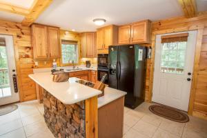 a kitchen with wooden cabinets and a black refrigerator at Hidden Hawk in Seven Devils +22 photos