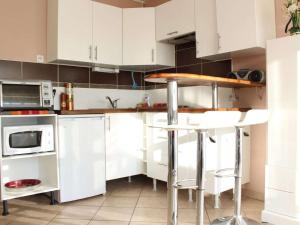 a kitchen with white cabinets and a counter with stools at Appartement La Rochelle, 2 pièces, 4 personnes - FR-1-246-555 in La Rochelle