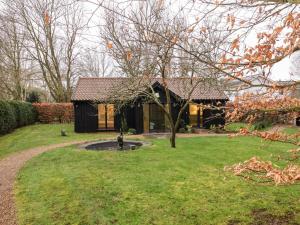 a house in a yard with a pond in the grass at Owl Cottage in Woodbridge