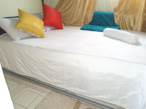 a white bed with colorful pillows on it at FonMark Haven in Webuye