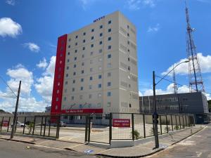 a tall white building with a red sign on it at San Martin Hotel in Uberlândia