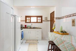 a kitchen with white cabinets and a table and a window at CASA CORAL SAQUAREMA in Saquarema