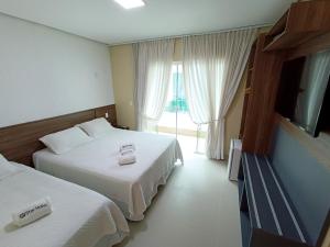 a hotel room with two beds and a flat screen tv at Star Hotel in Jericoacoara