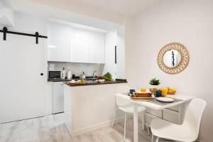 een witte keuken met een tafel en witte stoelen bij Apartamento Frida centro Gijón in Gijón