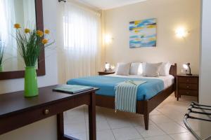 a bedroom with a bed and a desk with a vase of flowers at Villa Thaleia in Sivota