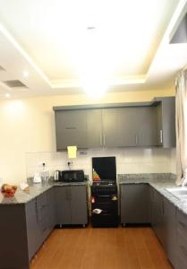 uma cozinha com armários cinzentos e um frigorífico preto em Sky Apartment kampala Feel At home em Kampala