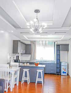 Sky Apartment kampala Feel At home في كامبالا: مطبخ مع طاولة وبعض الكراسي البيضاء