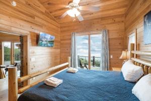 una camera da letto in stile baita di tronchi con letto e ventilatore a soffitto di Mountain Top Lodge a Beech Mountain